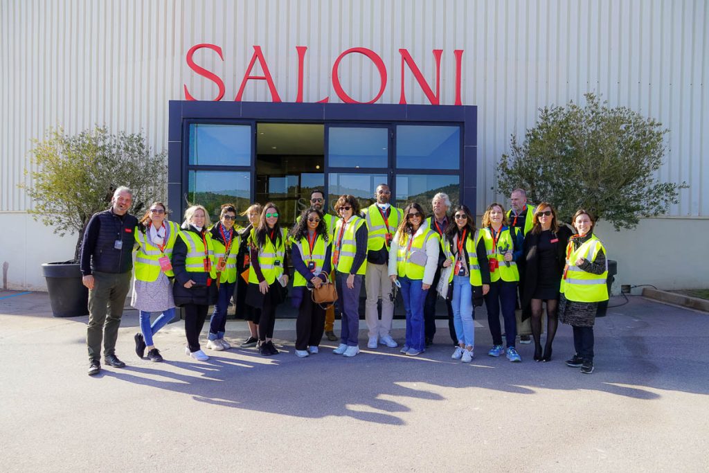 A group of people wearing safety vests standing in front of the Saloni building.